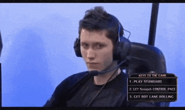 a man wearing headphones is sitting in front of a screen that says keys to the game on it
