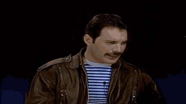 a man with a mustache is wearing a leather jacket and a striped shirt .