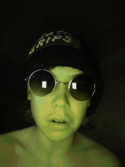 a person wearing sunglasses and a hat that says ' grips ' on it