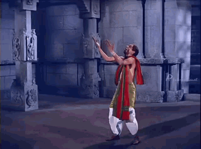 a man is standing in front of a stone wall in a temple and dancing .