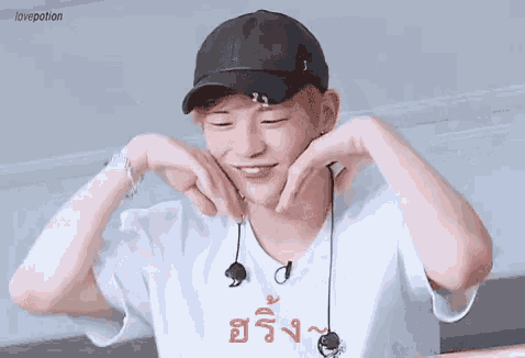 a man wearing a hat and earphones is making a heart shape with his hands .