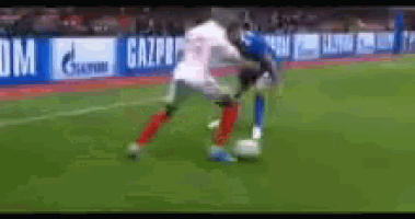 two soccer players are fighting for the ball on a field with a gazprom banner in the background .