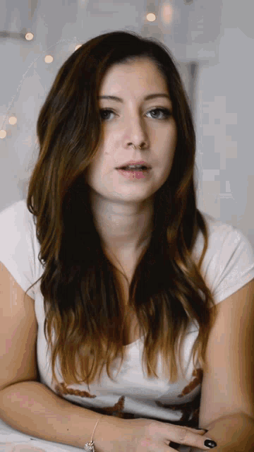 a woman with long brown hair is wearing a white shirt and black nails