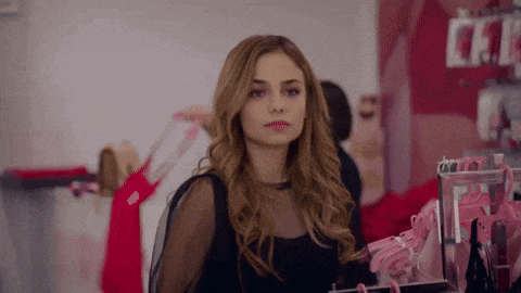 a woman in a black dress is looking at herself in a mirror .