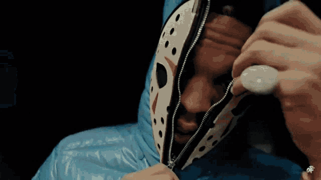 a person wearing a blue hooded jacket with a white face