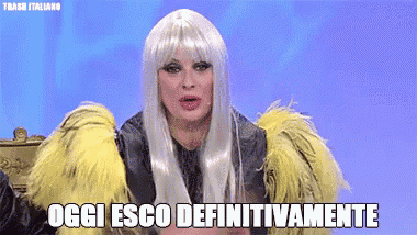 a woman wearing a wig and a fur coat with the words oggi esco definitivamente below her