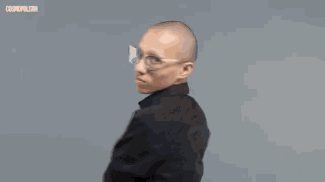 a bald man wearing glasses and a black shirt is clapping his hands .