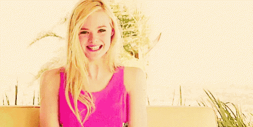 a woman in a pink tank top is smiling while sitting on a bench .