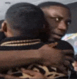 a man is hugging another man on a plane while holding a microphone .
