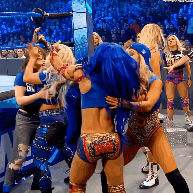 a female wrestler with blue hair is hugging another wrestler