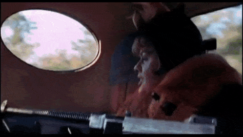 a woman in a fur coat is driving a car with a gun .