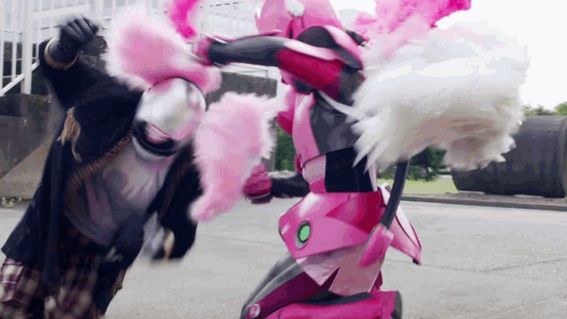 a woman in a pink robot costume is fighting a man in a black costume .