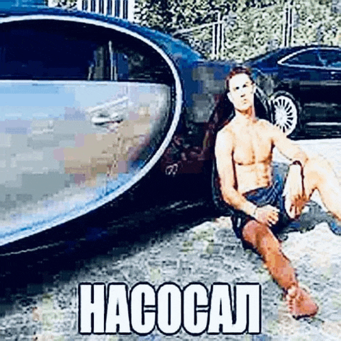 a shirtless man is sitting in the doorway of a car with his legs crossed .