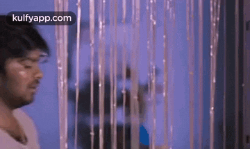 a man is standing in front of a pink curtain with tinsel hanging from it .