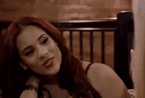 a woman with red hair and red lipstick is sitting in a chair .
