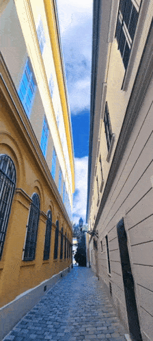 a narrow alleyway between two tall buildings on a sunny day