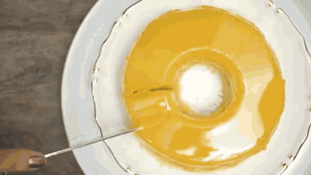 a white plate topped with a yellow donut with a hole in the middle