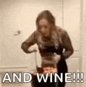 a woman is standing next to a cat and holding a wine glass .