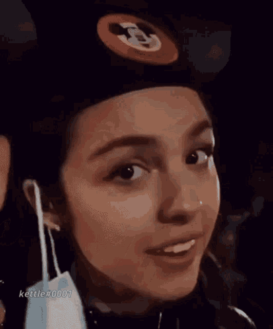 a woman wearing a hat and headphones is making a face .