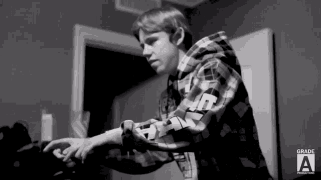 a black and white photo of a boy wearing a plaid shirt with the word grade a on the bottom