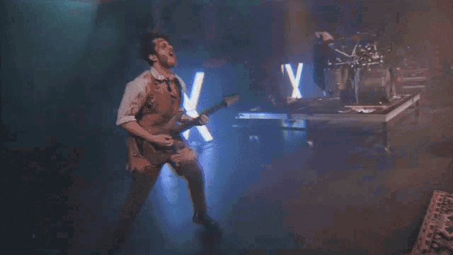 a man playing a guitar in front of a sign that says ' y ' on it