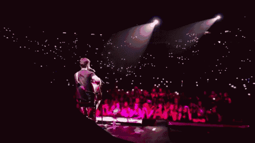 a man playing a guitar on a stage with a crowd watching