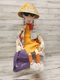 a stuffed doll wearing a straw hat and sunglasses is sitting on a wooden table .