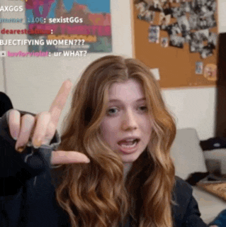 a woman is giving a middle finger in front of a poster that says sexistggs on it