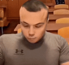 a man wearing a grey under armour shirt is sitting in a classroom