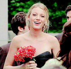 a woman in a black strapless dress holds a bouquet of red flowers