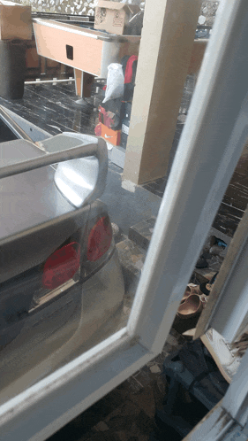 a car is parked in front of a stack of boxes including one that says ' coca-cola ' on it