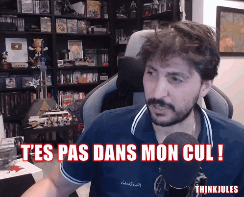a man sitting in front of a microphone with the words t'es pas dans mon cul written below him