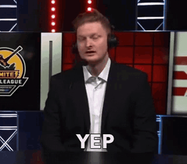 a man in a suit and headphones is standing in front of a microphone and says yep .