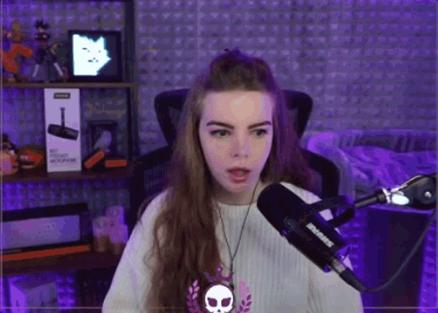 a woman sitting in front of a shure microphone in a purple room