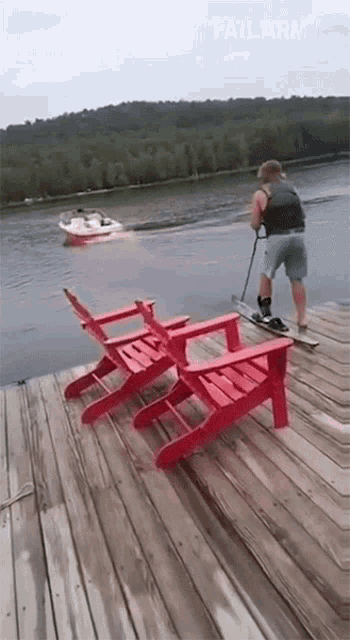 a man is standing on a dock with a boat in the background