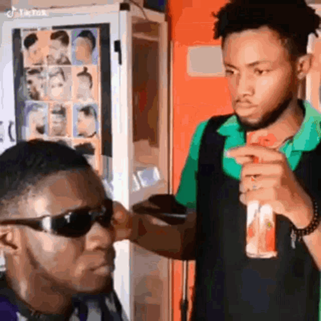 a man wearing sunglasses is getting his hair cut by a barber in a barber shop .