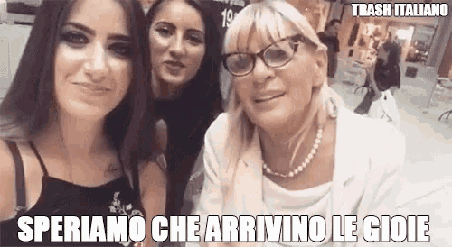 three women are posing for a picture together and one of them is wearing glasses and a pearl necklace .