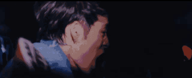 a man is standing in a dark room with a blue light behind him .