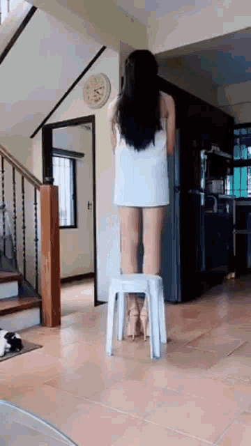 a woman in a towel is standing on a stool in a living room