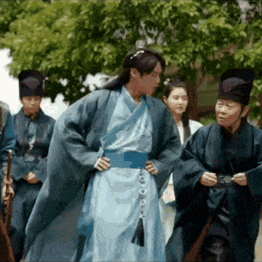a man in a blue kimono stands in front of a group of men in black hats
