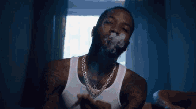 a man in a white tank top is smoking