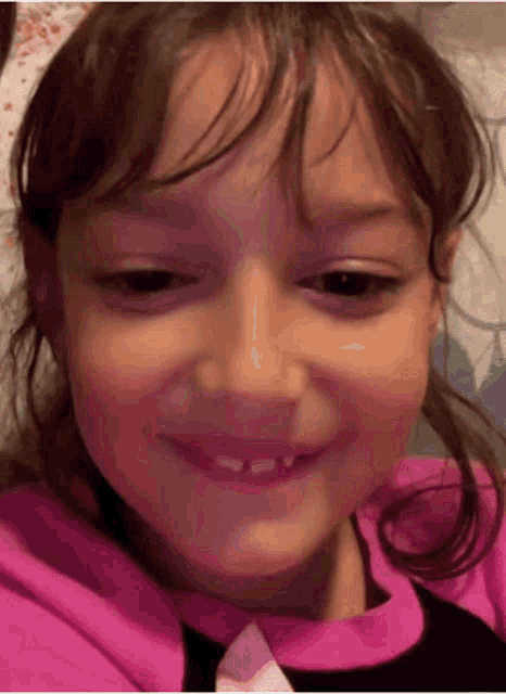 a little girl with missing teeth is smiling and making a funny face