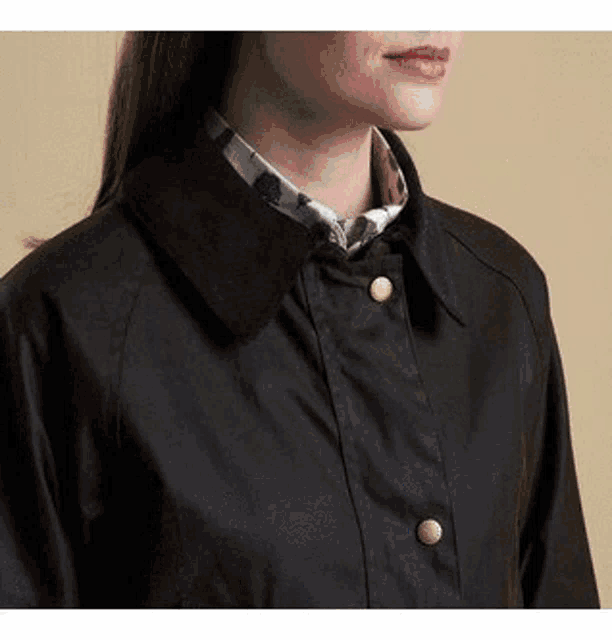 a close up of a woman wearing a black jacket with buttons on the front .