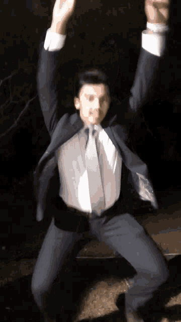 a man in a suit and tie is jumping in the air with his arms in the air