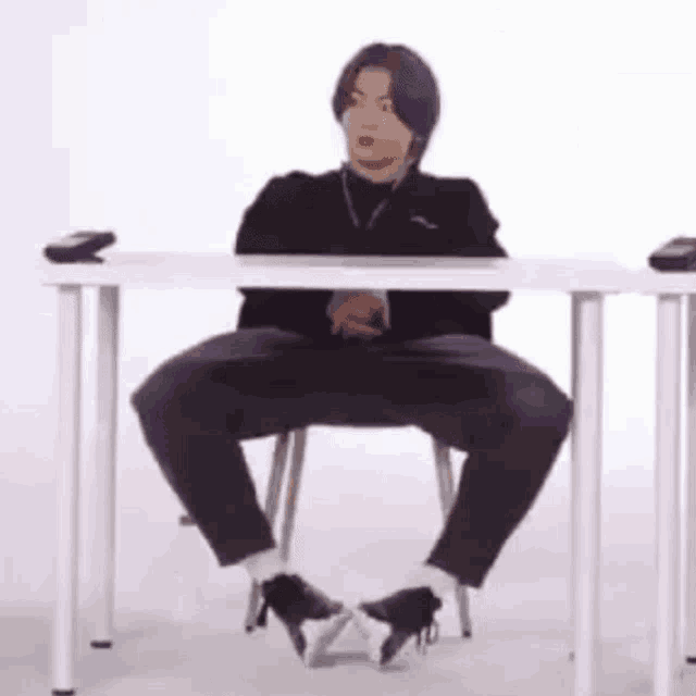 a person is sitting at a table with their legs crossed and their feet crossed .