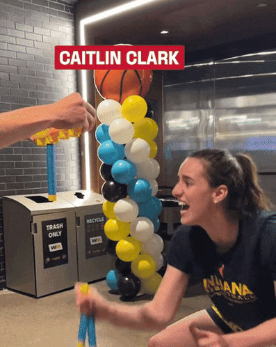caitlin clark is playing a game with balloons and a basketball in the background