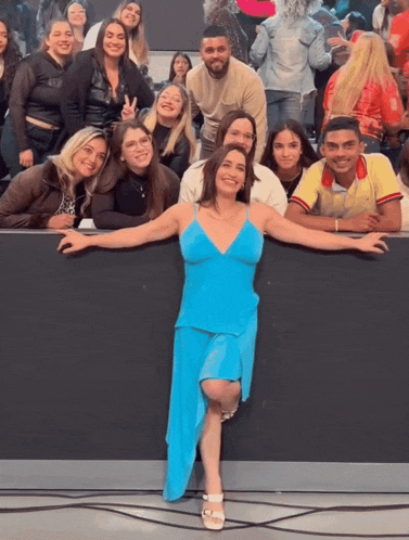 a woman in a blue dress is posing for a photo with a group of people