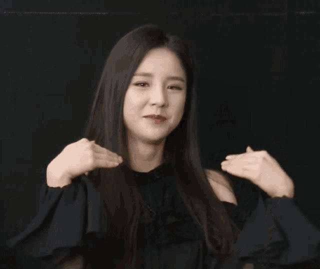 a woman in a black off the shoulder top is making a funny face