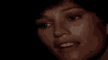 a close up of a woman 's face smiling with a black background .
