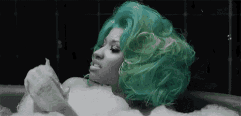 a woman with green hair is taking a bath in a bathtub filled with soap bubbles .